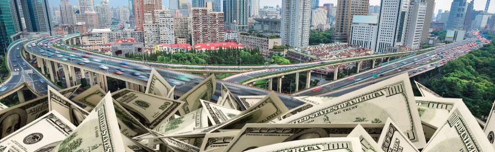 Piles of US Currency superimposed over a city with lots of bridges and roads